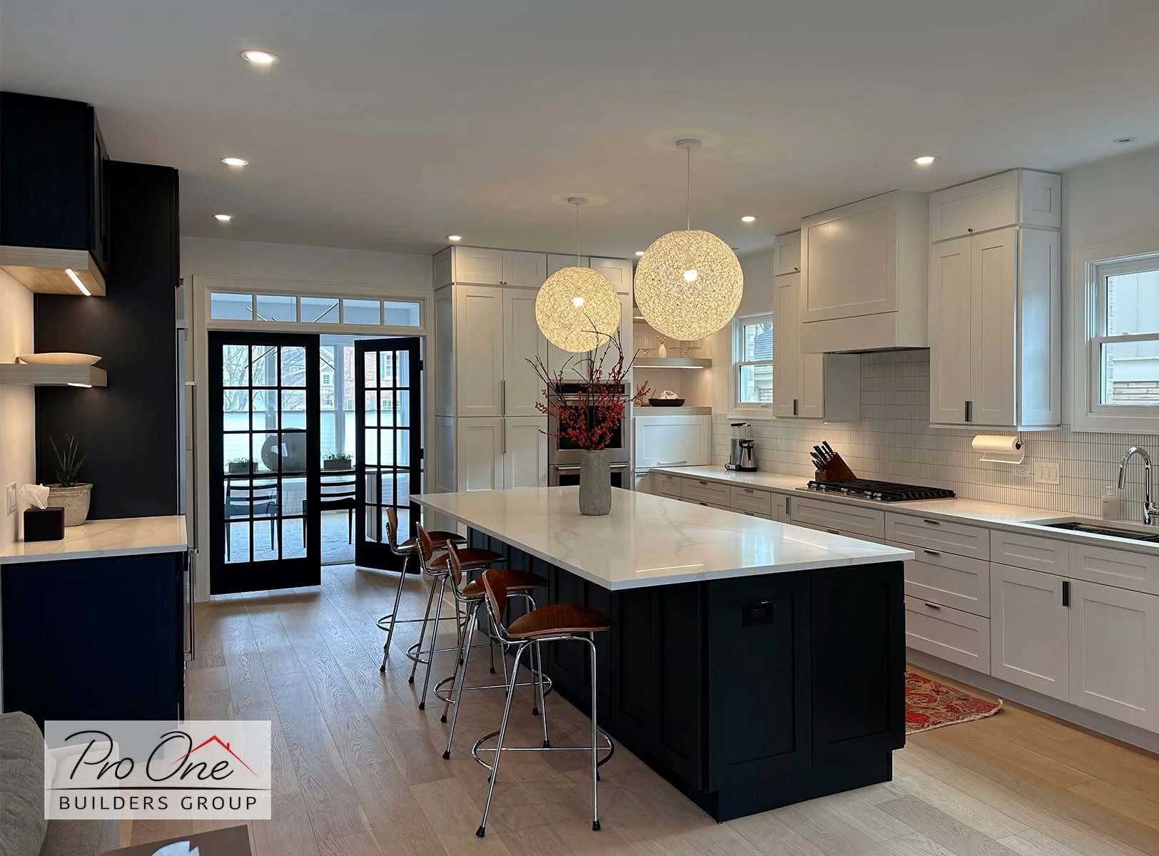 Modern kitchen with white cabinets, black island, quartz counters, and pendant lights