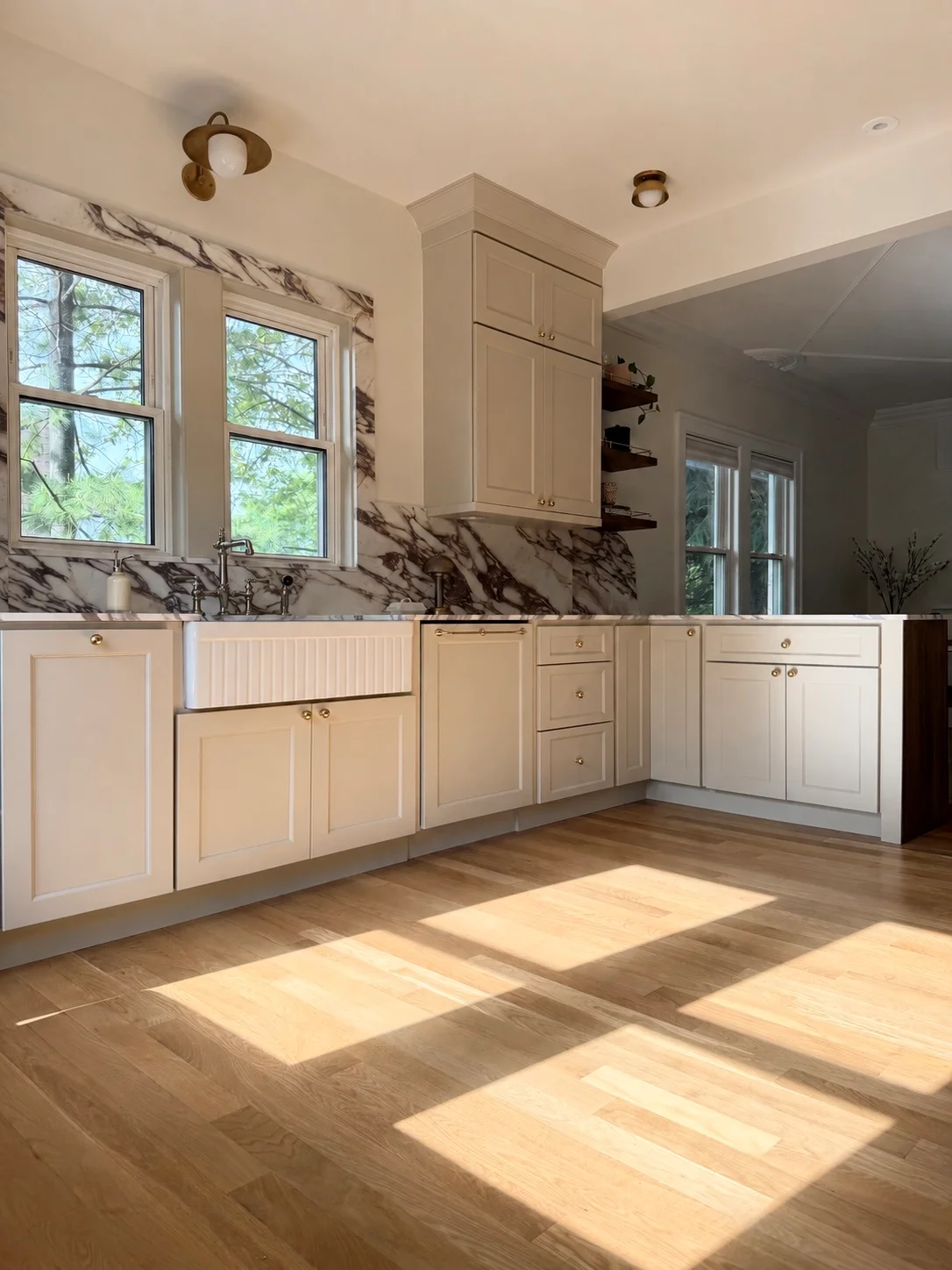 Kitchen with cream cabinetry, marble backsplash, hardwood floors, and large windows
