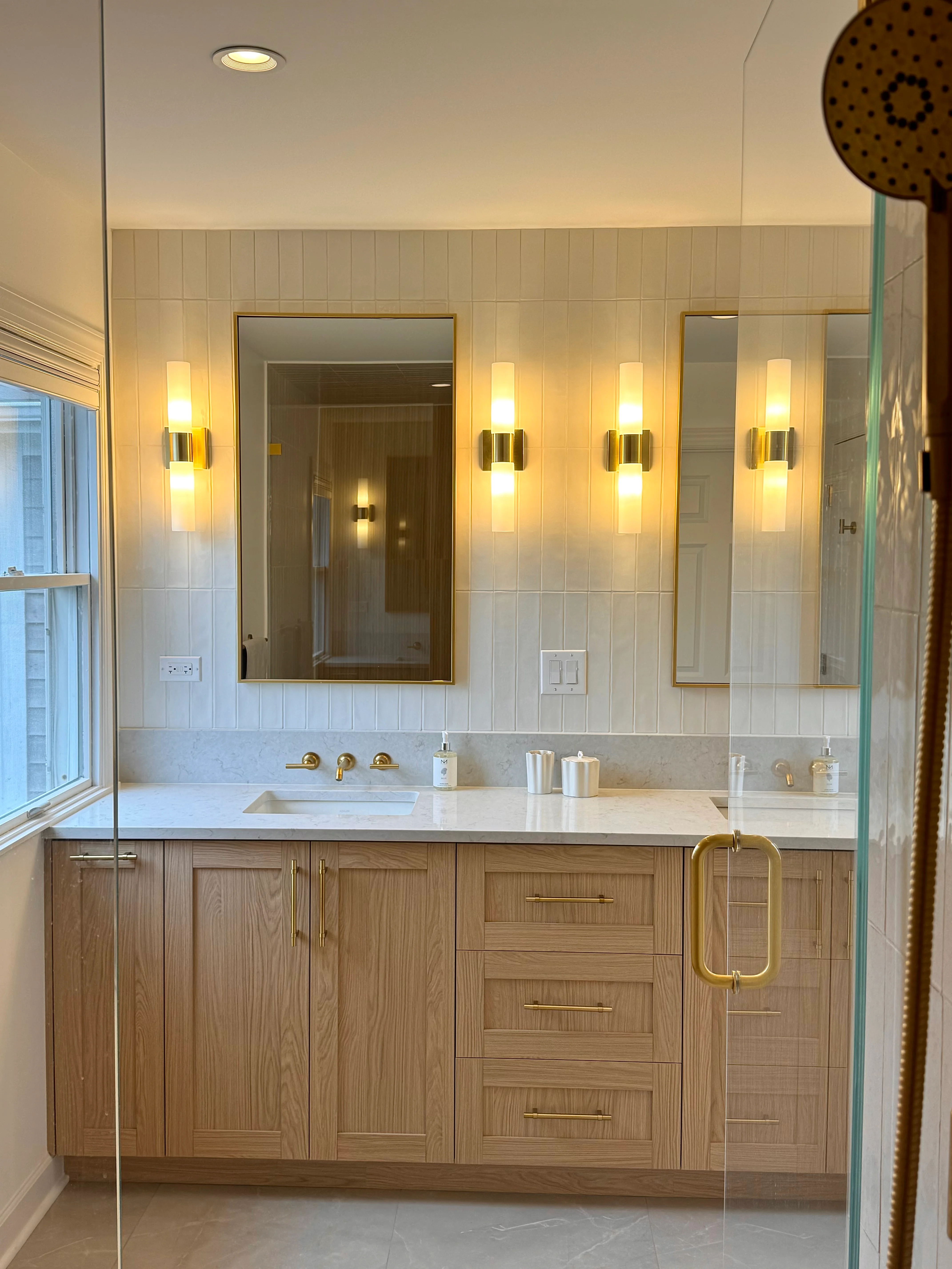 Master bathroom with wood cabinetry, marble counters, subway tile, and brass fixtures