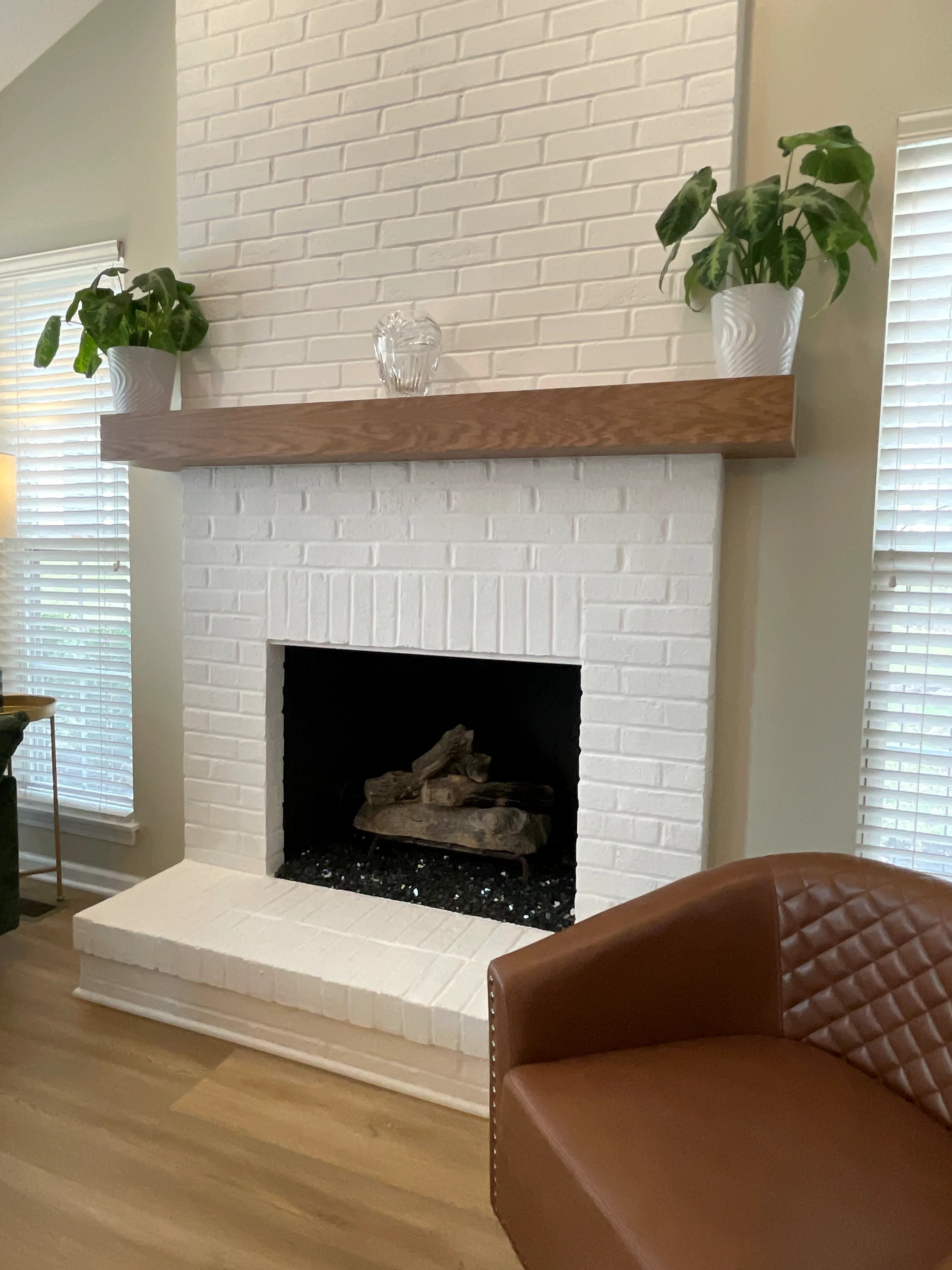 White brick fireplace with dark wood mantel shelf and black insert surround