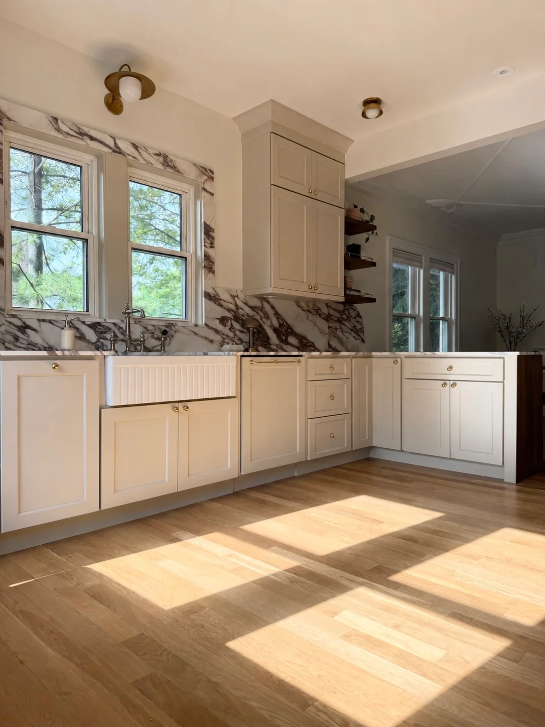 Modern kitchen with cream cabinets, marble backsplash, hardwood floors, and large windows