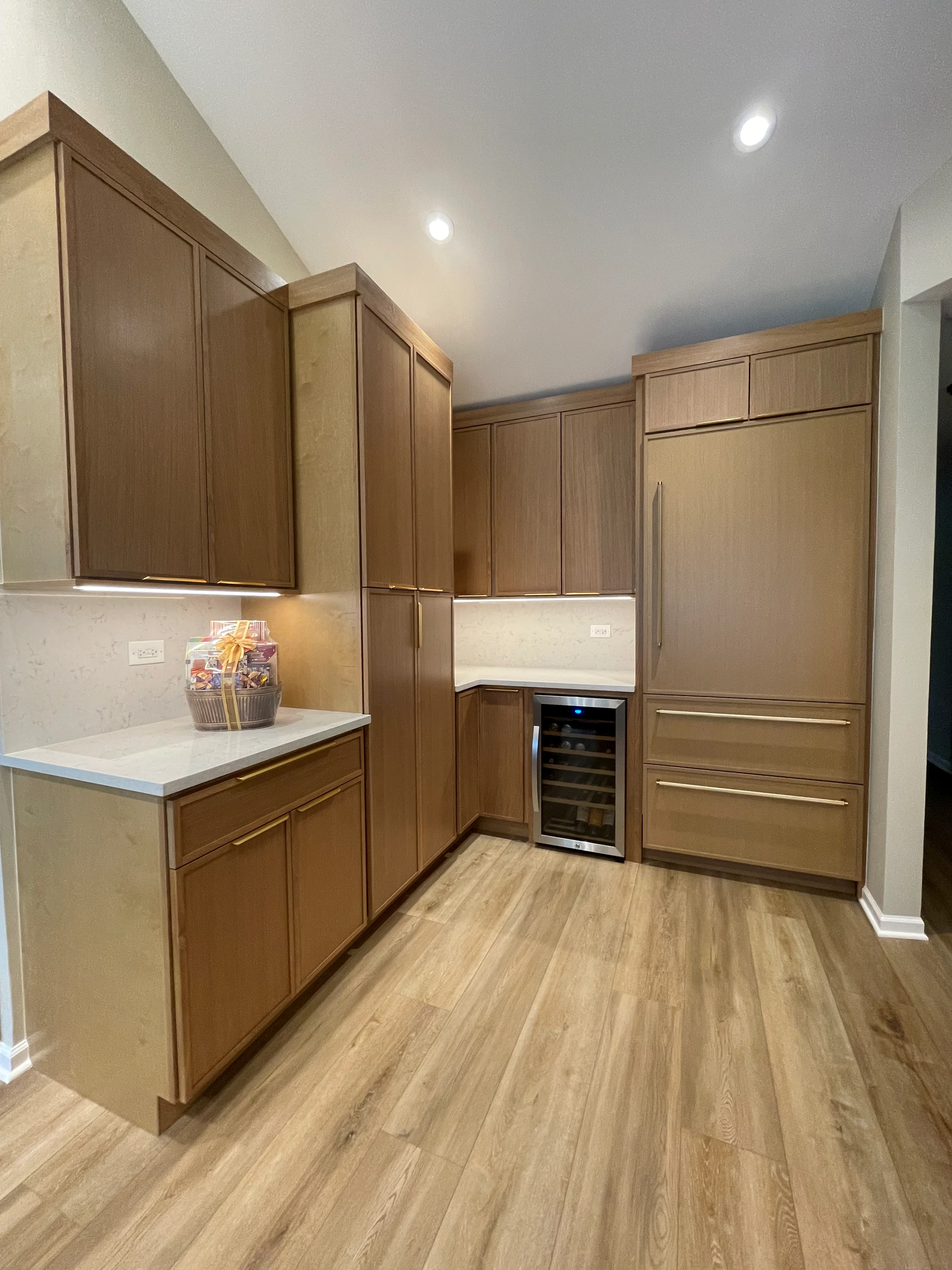 Custom wood cabinetry pantry with white countertop, wine cooler, and recessed lighting