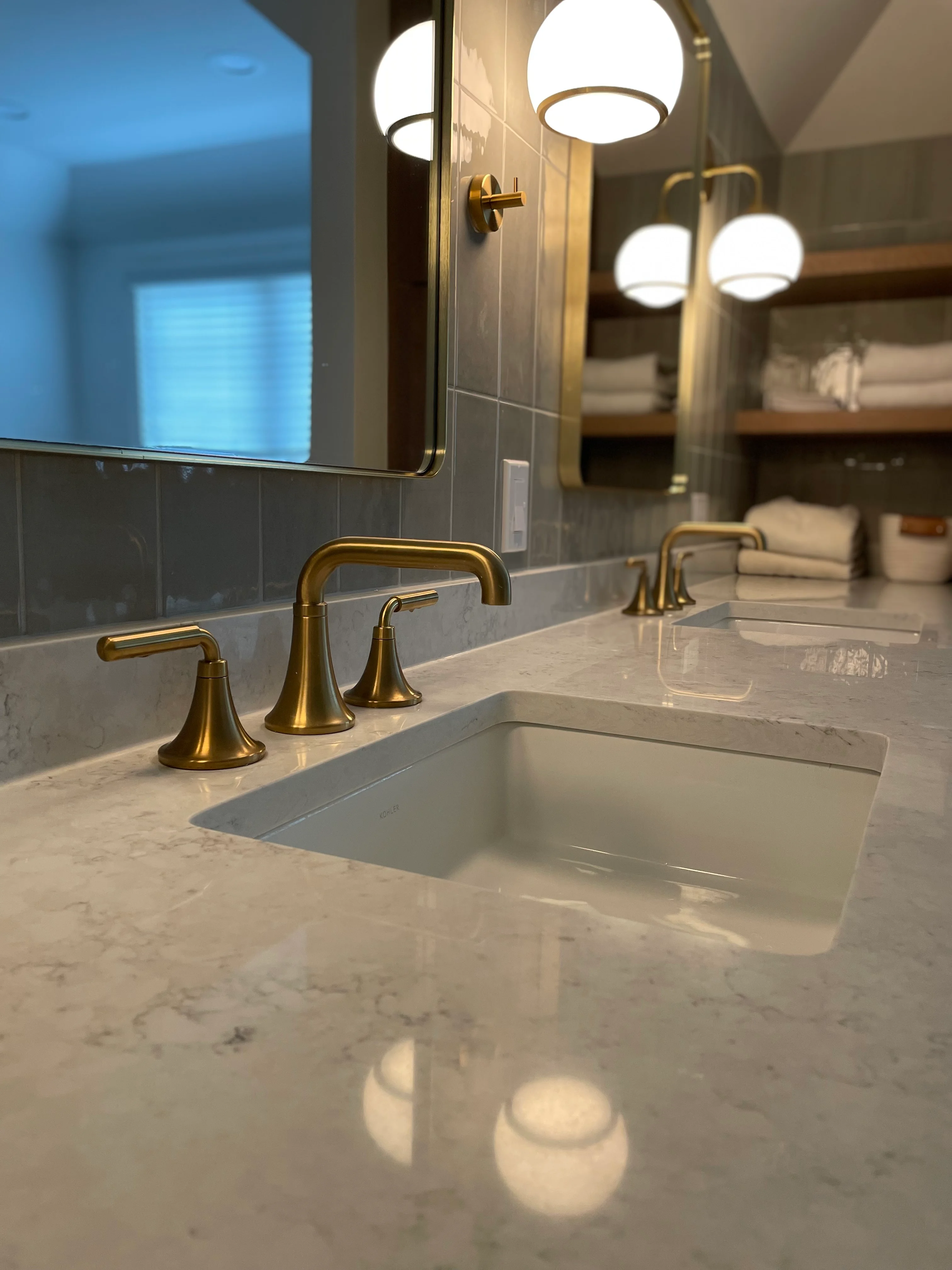 Marble countertop with brass faucet, tile backsplash, and recessed lighting in renovated bathroom