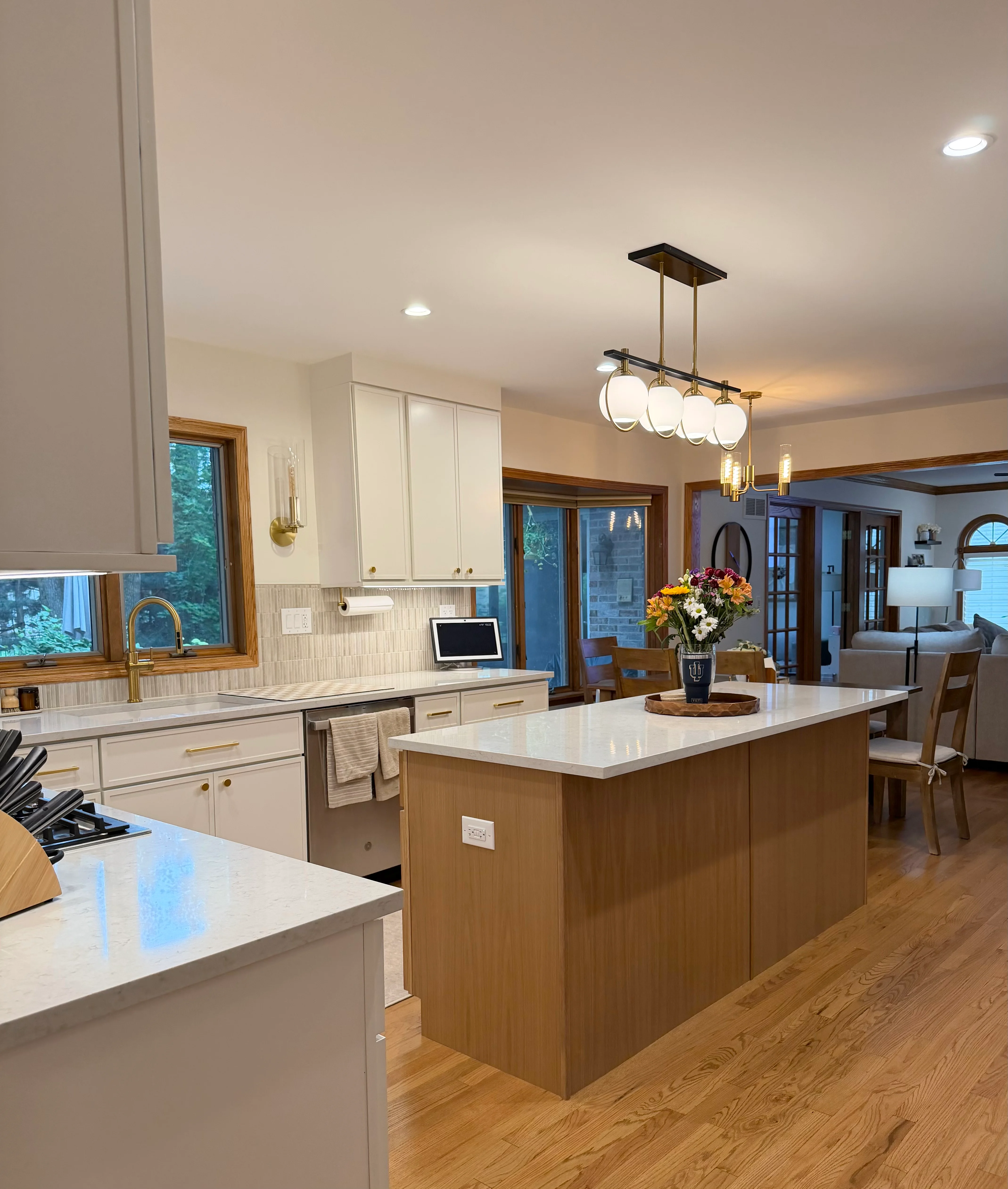 Modern kitchen with white cabinetry, walnut island, quartz counters, and pendant lighting