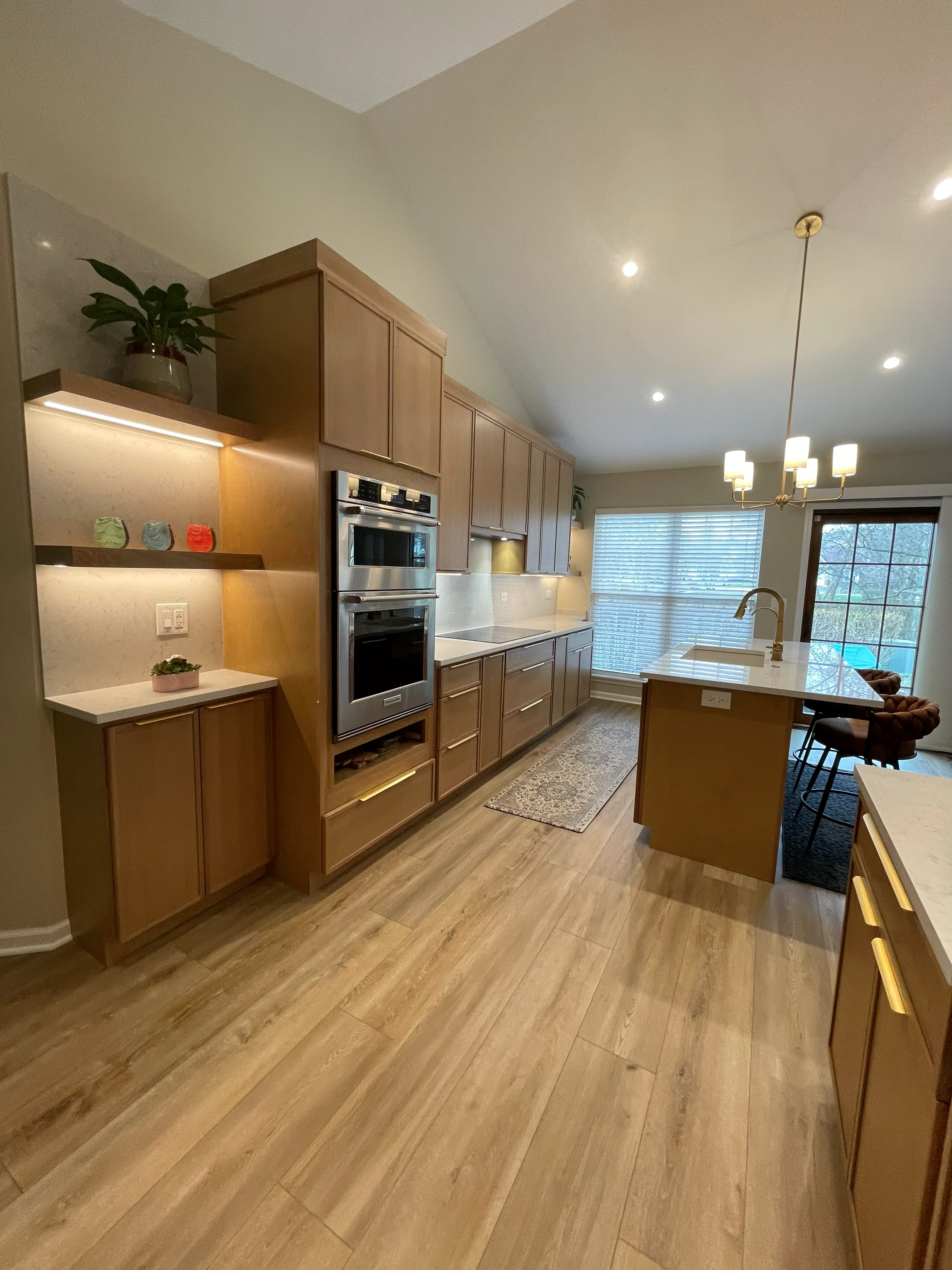Kitchen with wood cabinetry, stainless steel appliances, quartz counters, and vinyl plank flooring