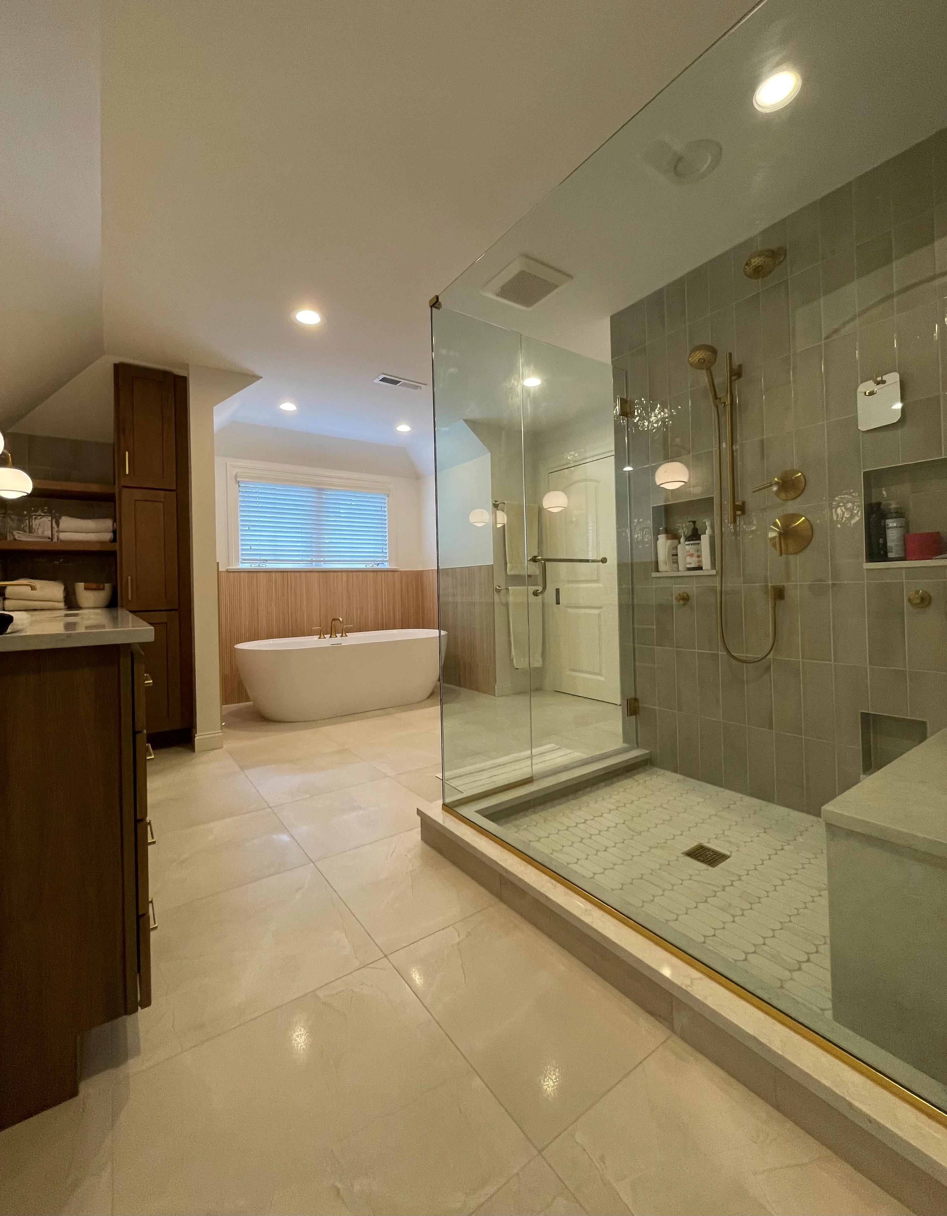 Master bathroom with frameless glass shower, gray tile walls, white mosaic floor, and freestanding soaking tub