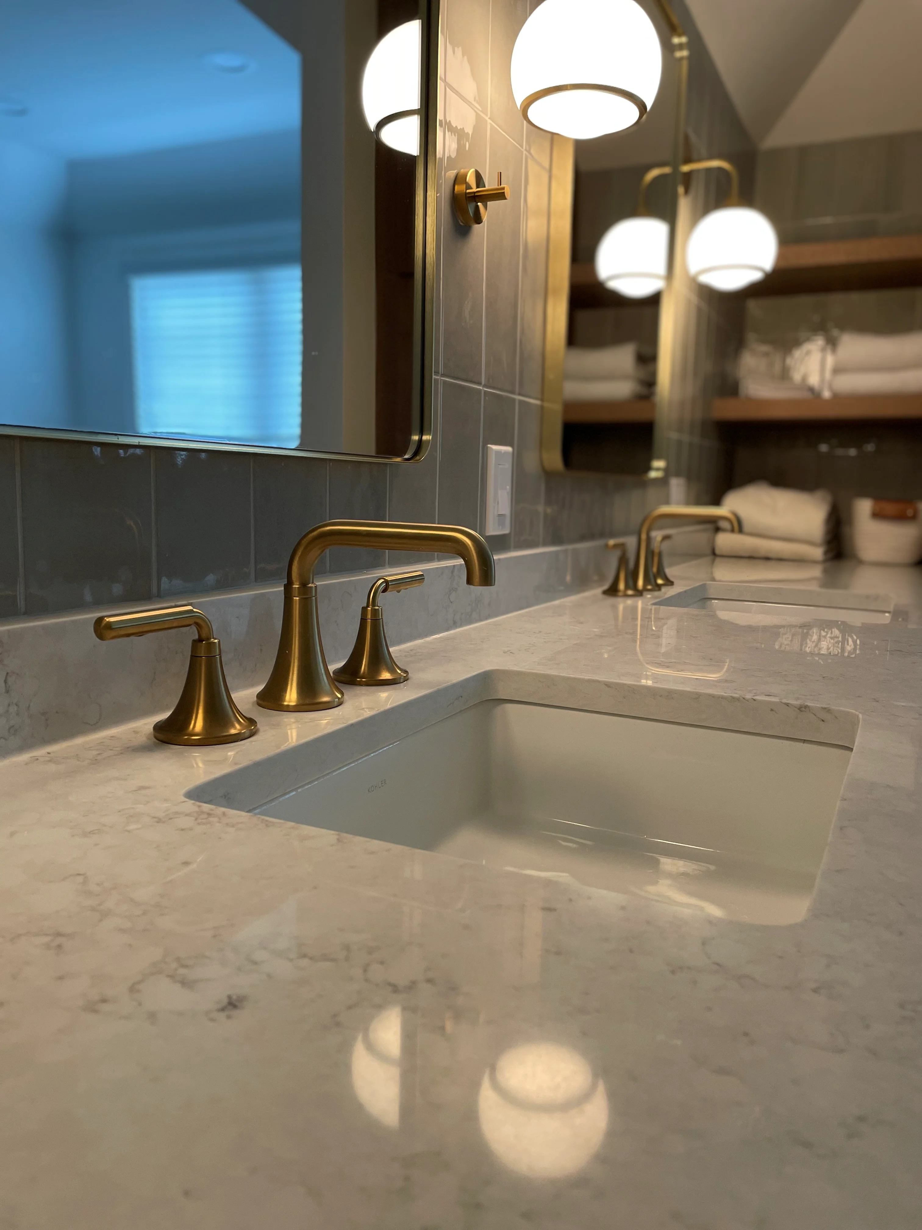 Marble bathroom countertop with brass faucet, tile backsplash, and recessed lighting
