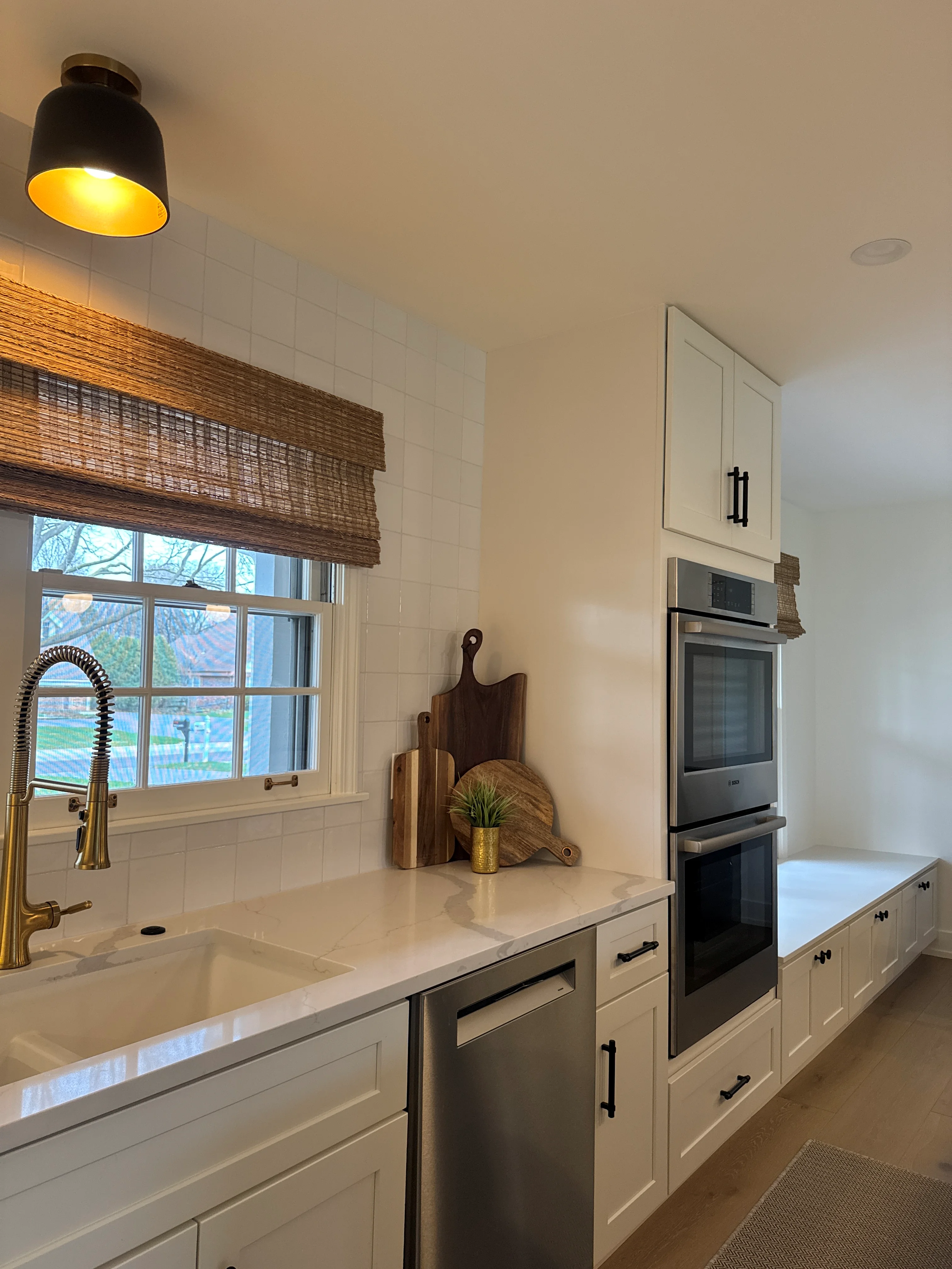 White kitchen with quartz counters, subway tile backsplash, stainless steel appliances, and custom cabinetry