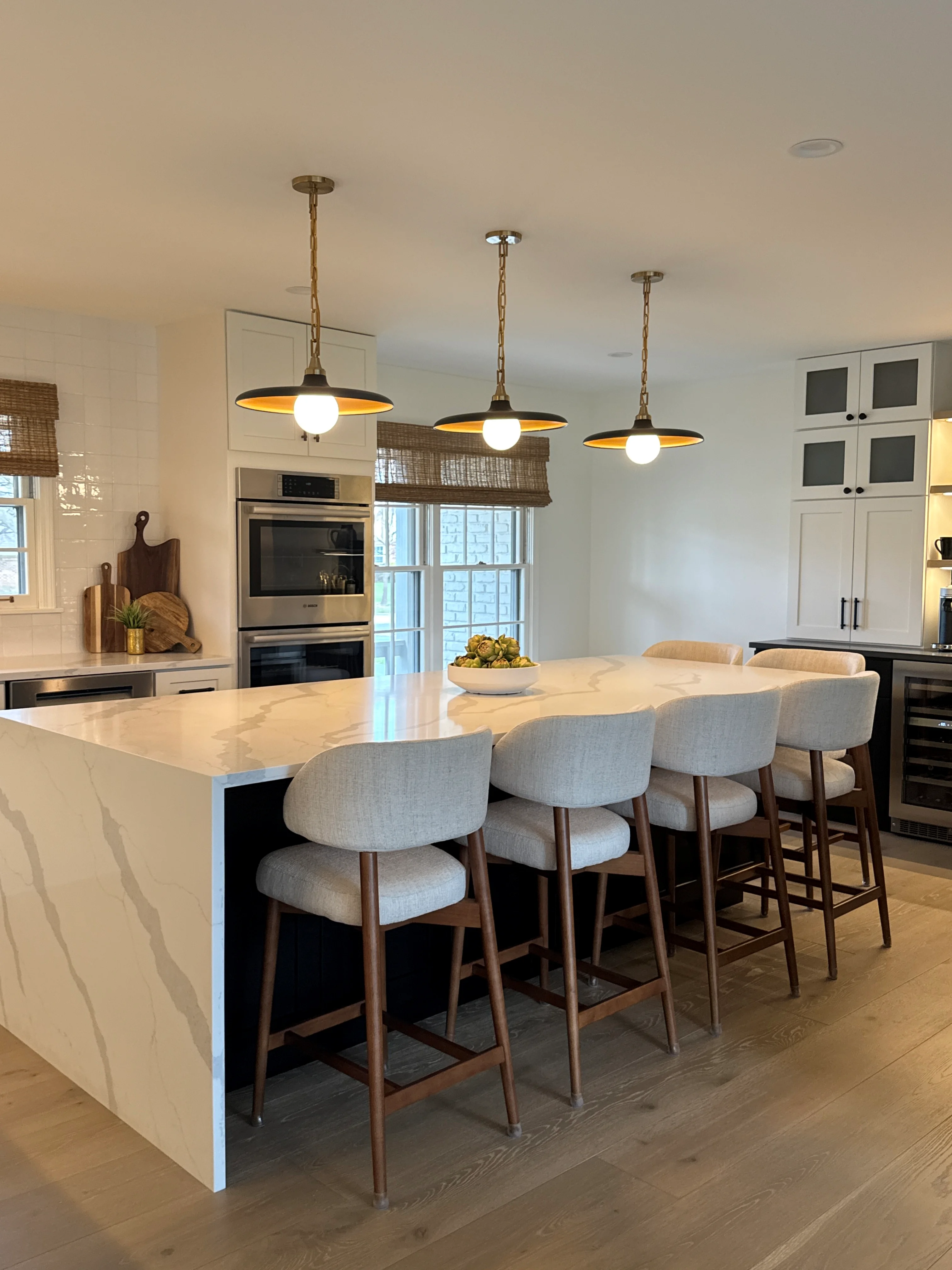 Modern kitchen with marble island, white cabinetry, stainless steel appliances, and pendant lighting