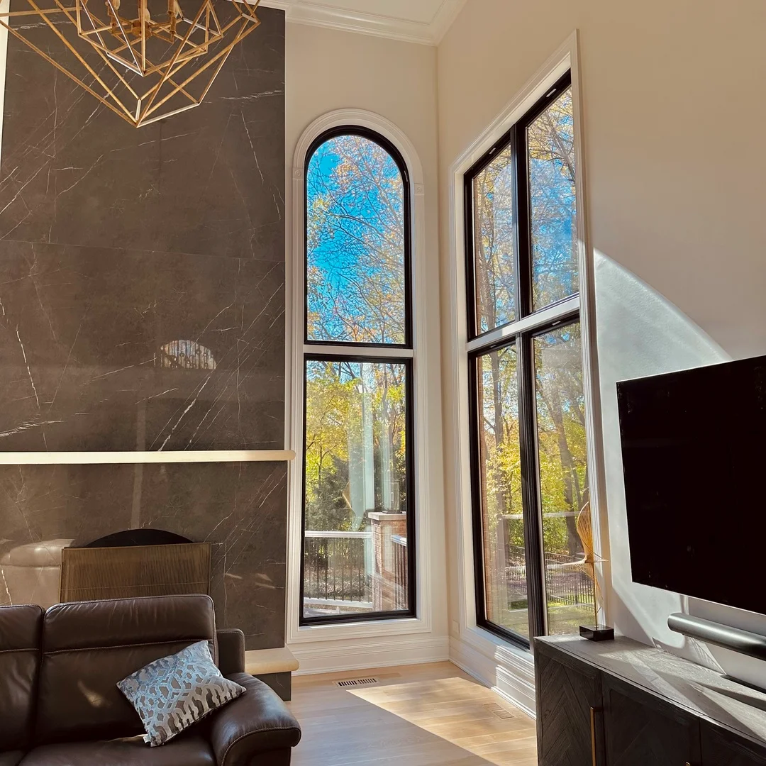 Dark marble accent wall, custom black-framed windows, hardwood flooring, and modern interior finishes