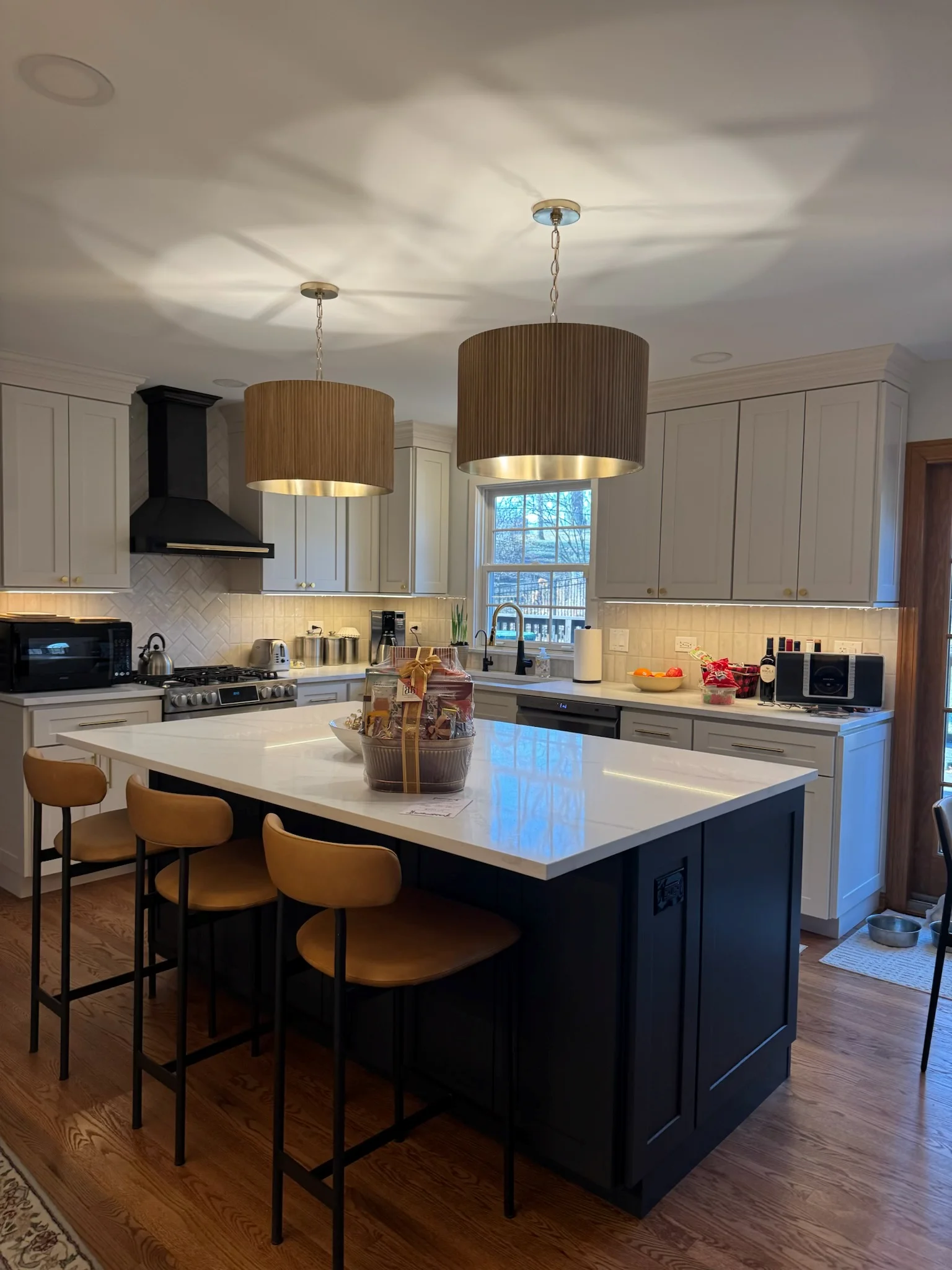 Modern kitchen with white cabinets, black island, quartz counters, and wood pendant lights