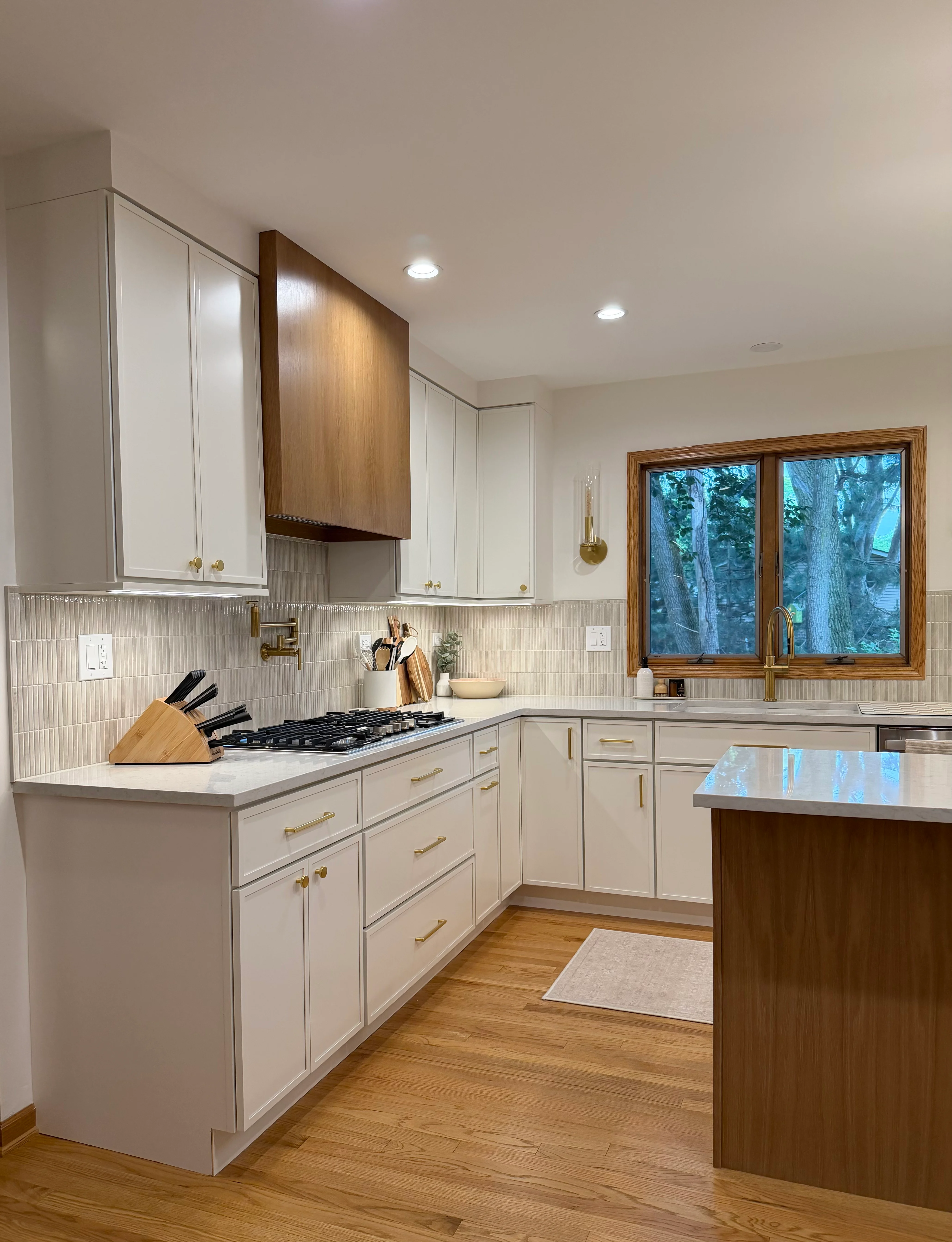 Modern kitchen with cream cabinets, white counters, and dark wood island with gas cooktop